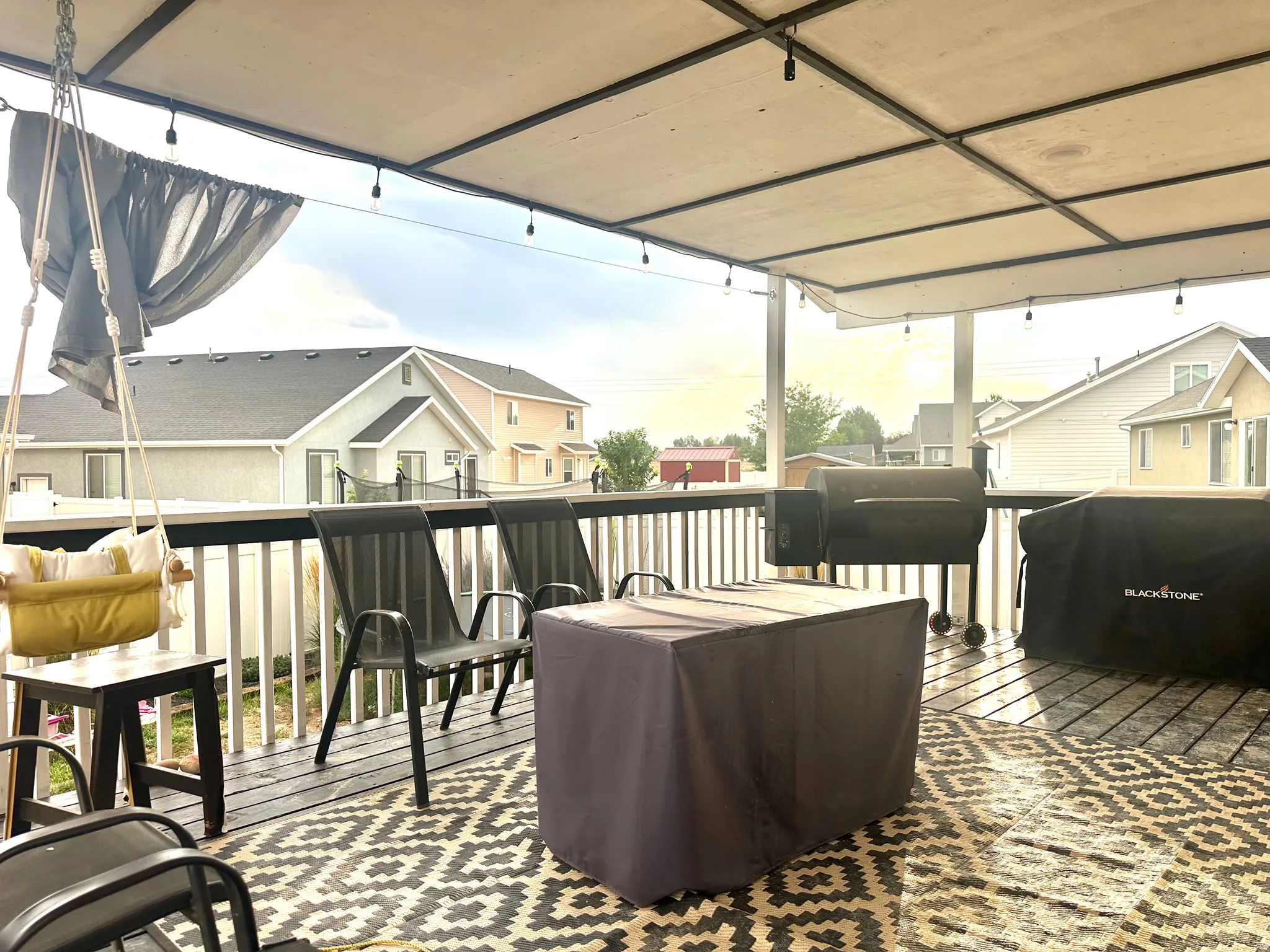 Covered deck with a slatted railing, overhead lighting, and a partial privacy screen
