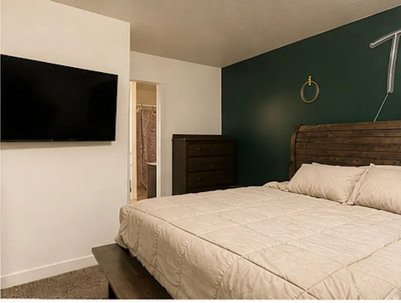 Accent wall with deep green paint and a durable wood-finish bed frame