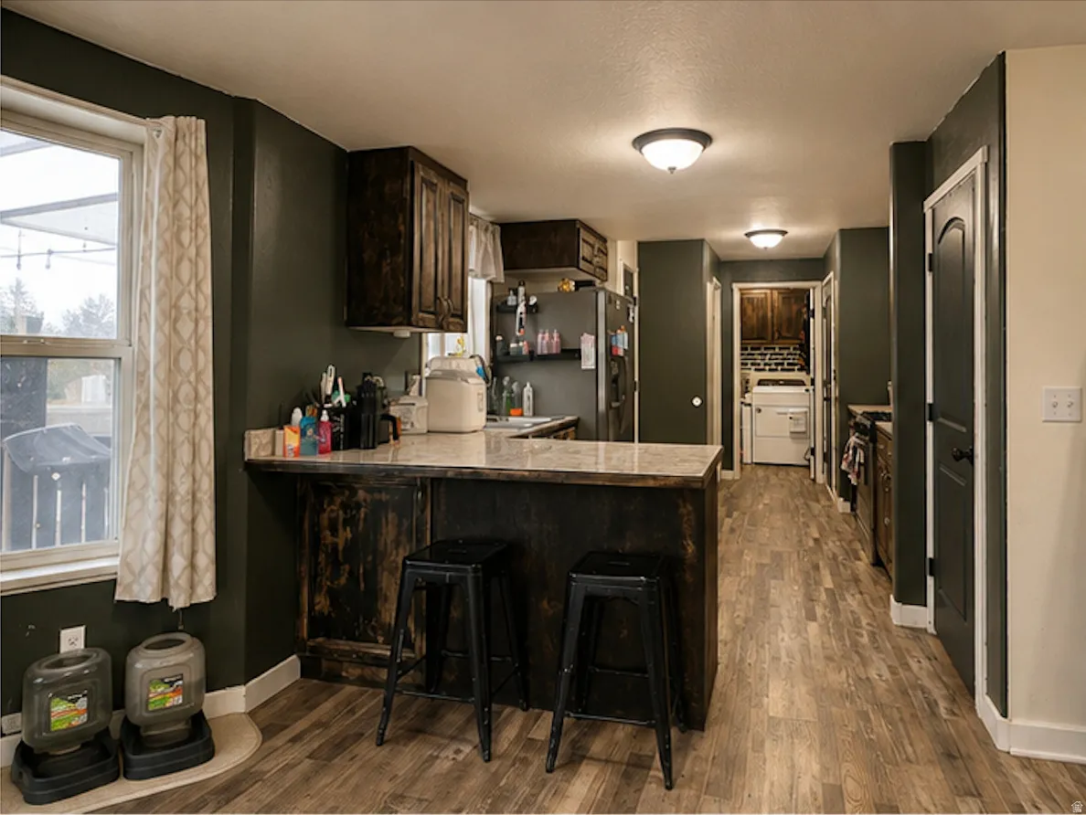 Kitchen featuring wood-finish flooring, dark cabinetry, and a central island with a light-colored countertop