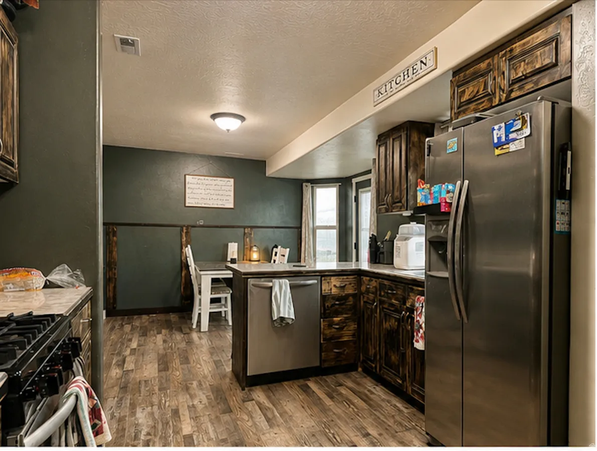 Kitchen featuring wood-finish flooring, dark wood cabinetry, and stainless steel appliances