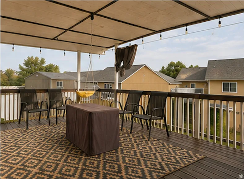 Expansive outdoor deck featuring dark wood-finish flooring, white and dark wood railings, and a fabric-covered pergola