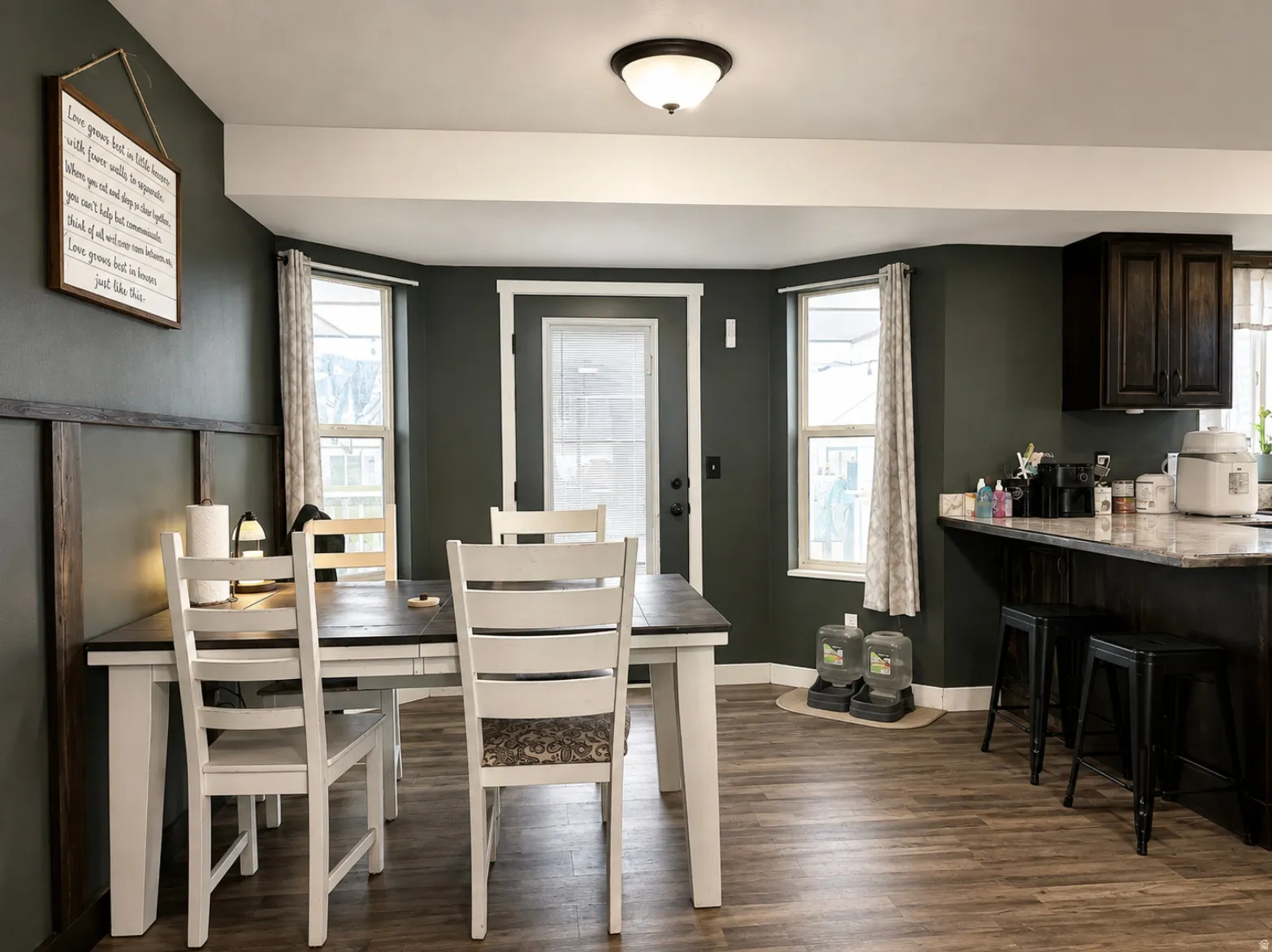 Wood-finish flooring, dark wall paneling, built-in upper cabinetry, and a countertop with seating