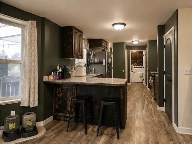Kitchen featuring wood-finish flooring, dark cabinetry, and a central island with a light-colored countertop