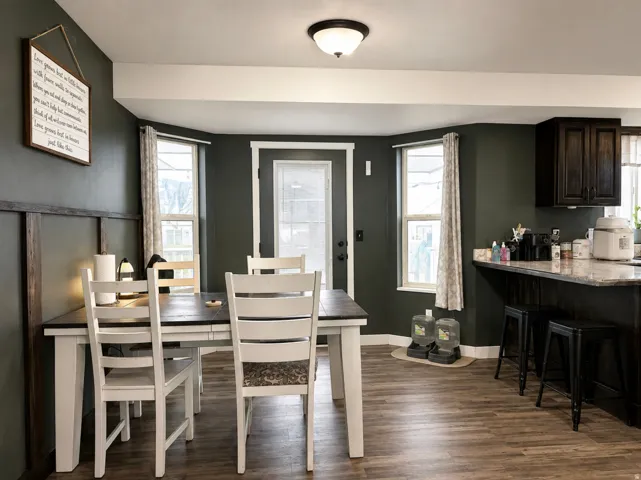 Wood-finish flooring, dark wall paneling, built-in upper cabinetry, and a countertop with seating