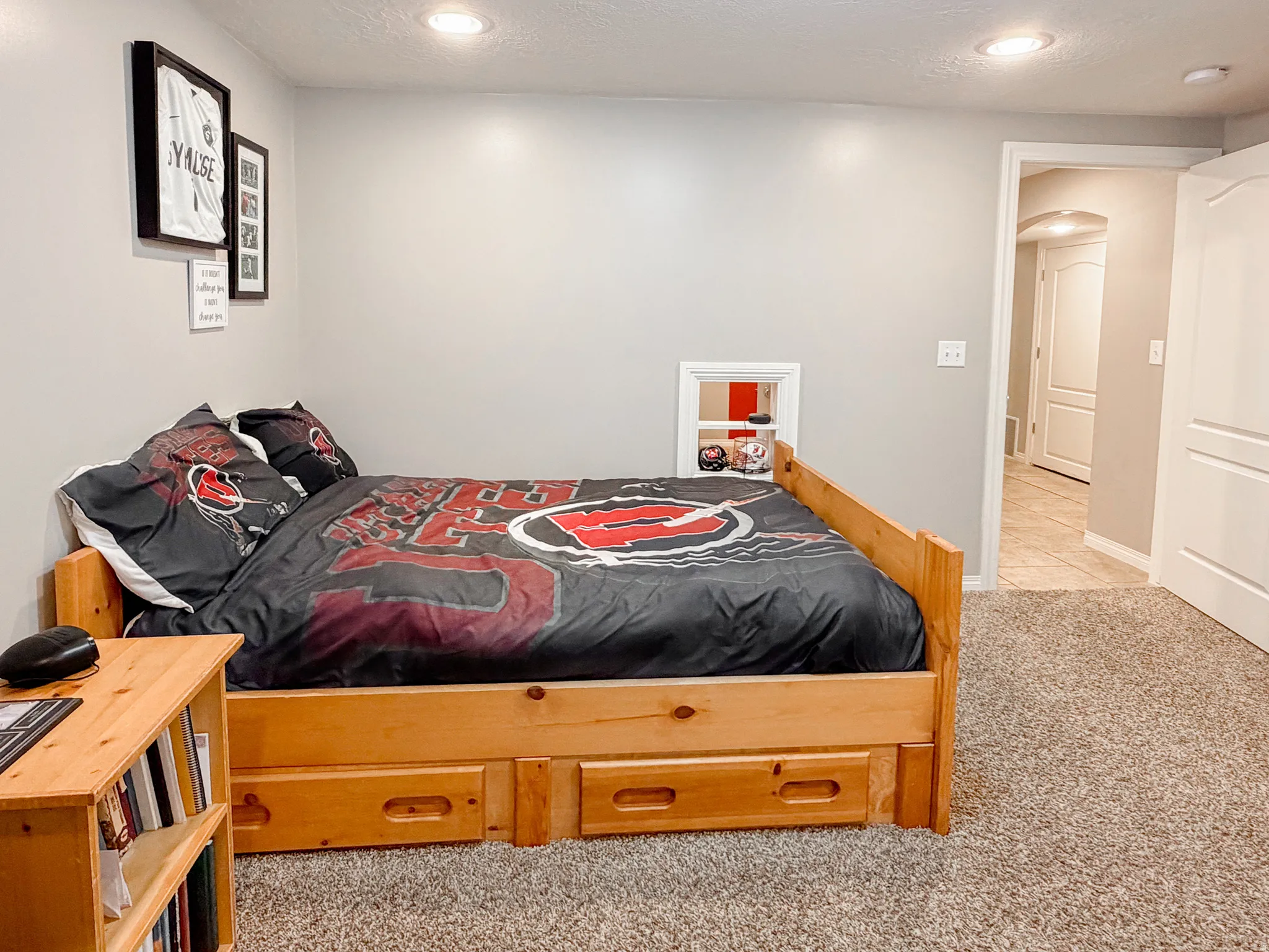 Recessed ceiling lighting, light gray wall paint, built-in wall niche, plush carpet flooring, and a white interior door