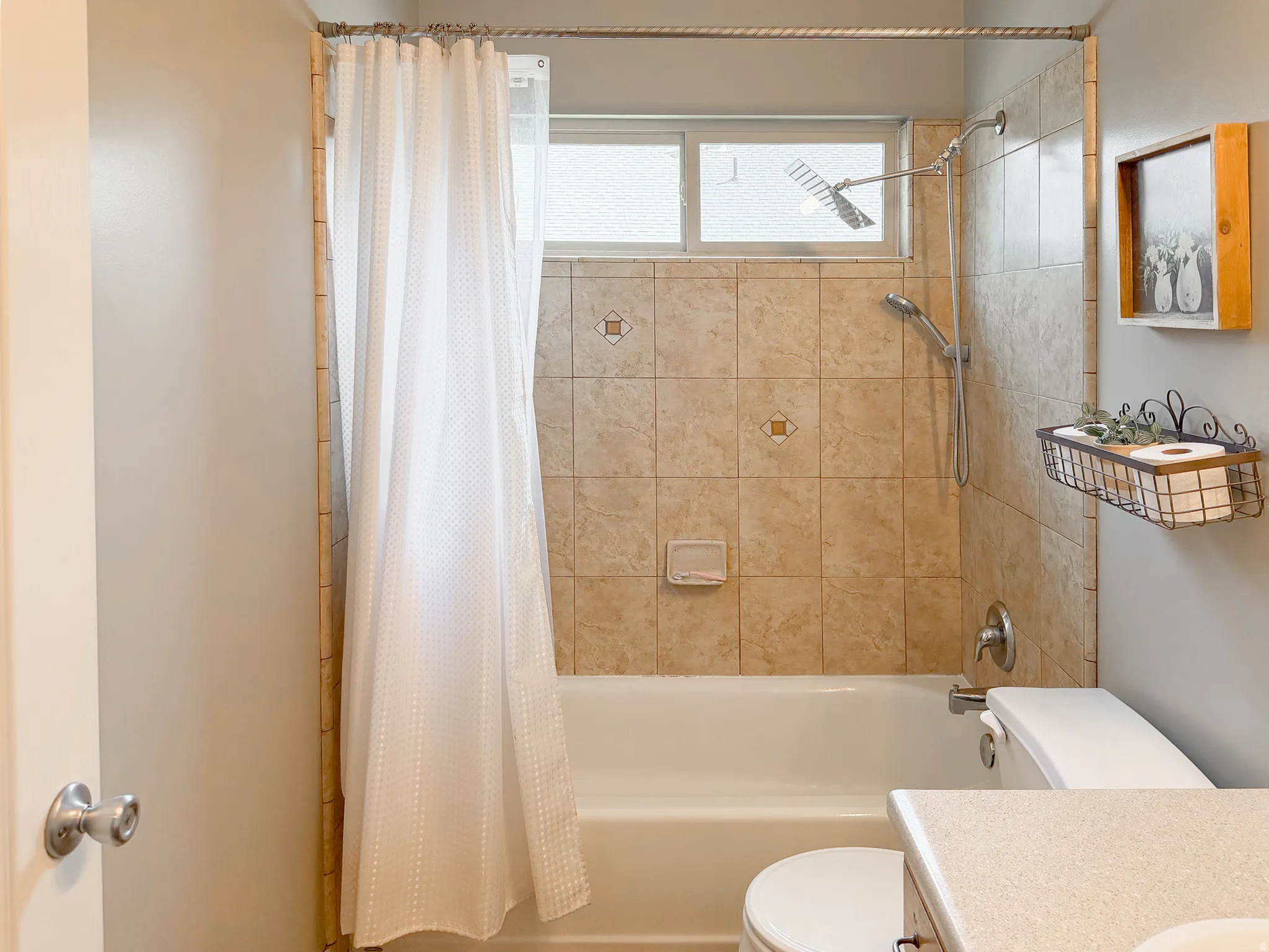Bathtub with tiled surround, dual shower heads, and an opaque window