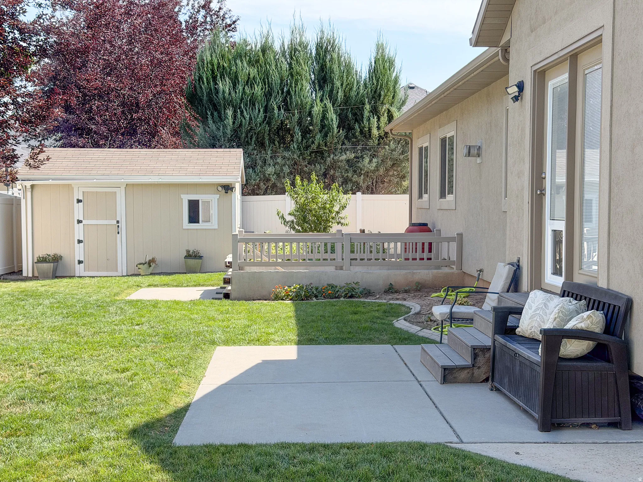 Expansive backyard featuring a concrete patio, grassy lawn, and a detached storage shed