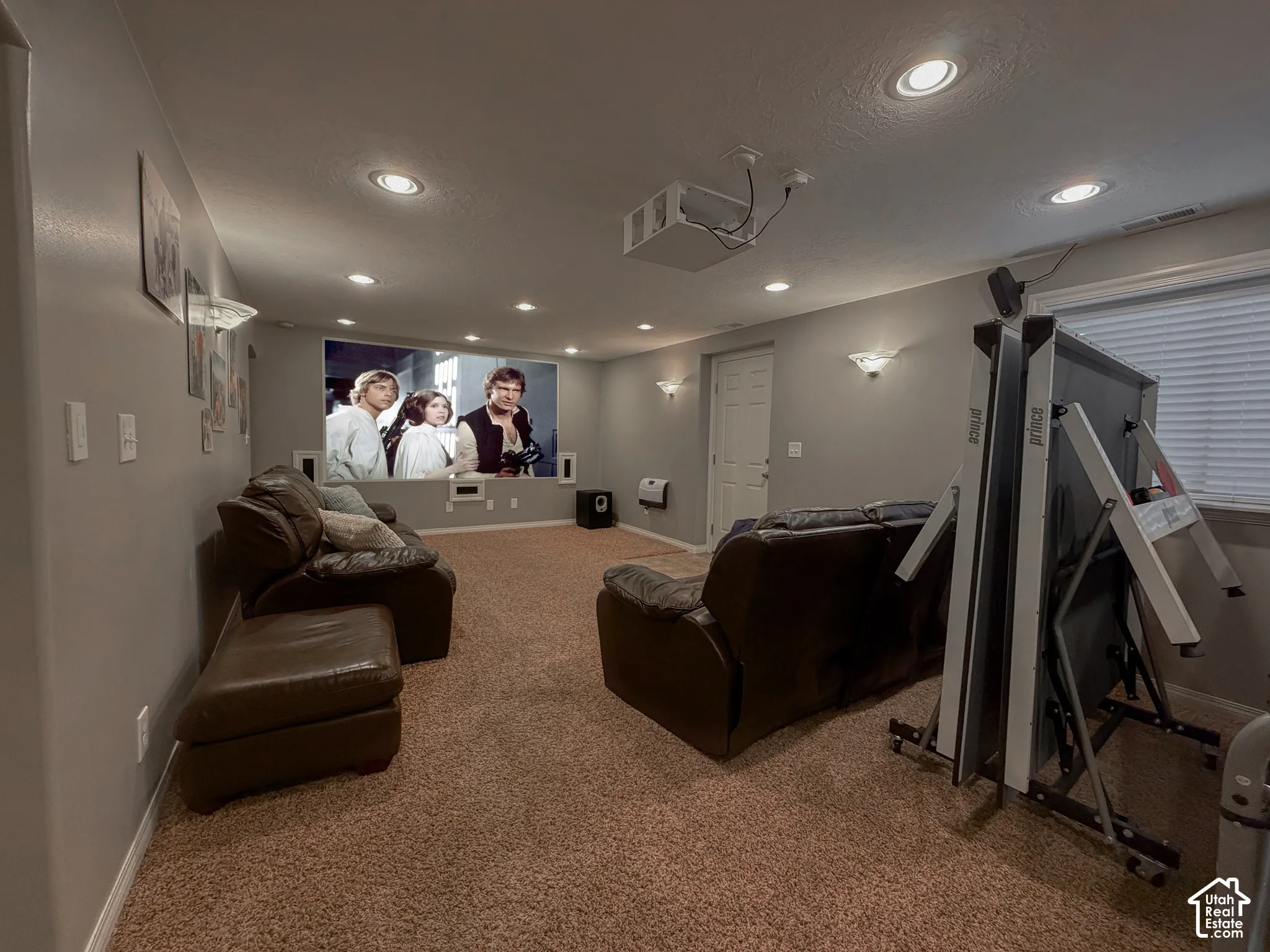 Recessed lighting, wall-mounted sconces, projector, and screen offer an entertainment-ready space