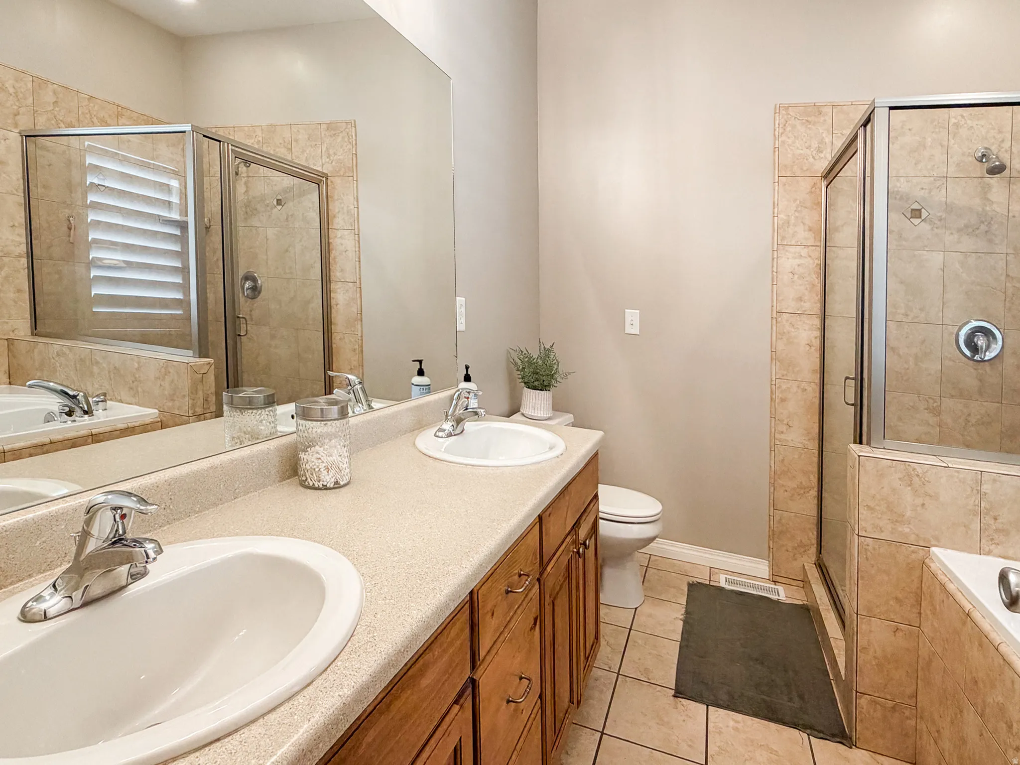 Dual vanity with undermount sinks, wood-finish cabinetry, and expansive mirror
