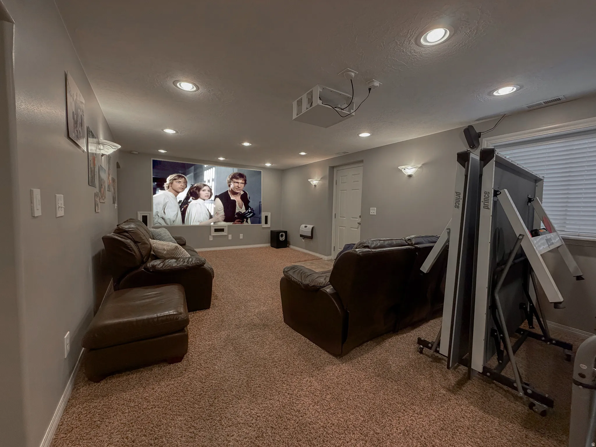 Recessed lighting, wall-mounted sconces, projector, and screen offer an entertainment-ready space