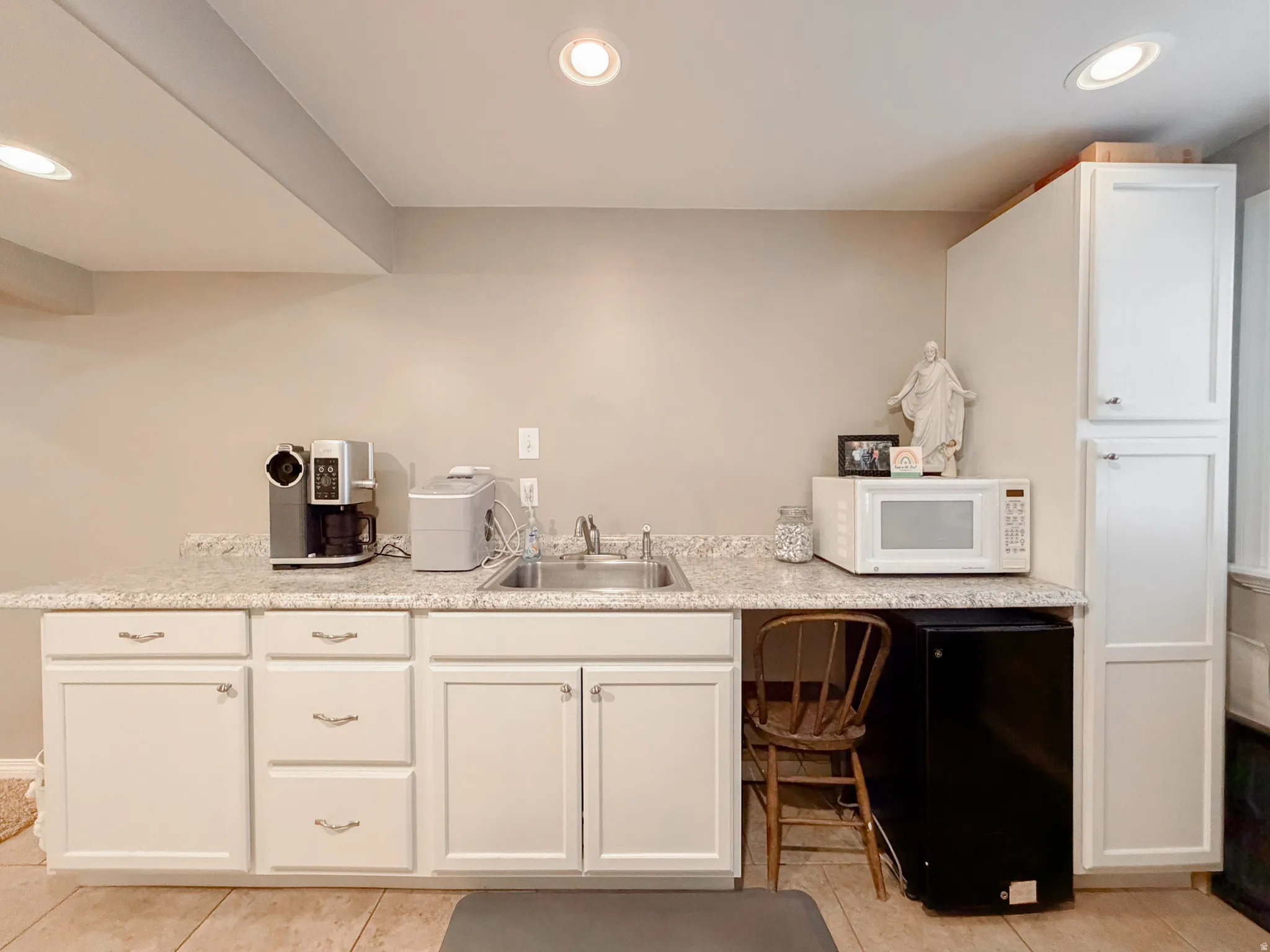 White cabinetry with silver-tone pulls, speckled countertop, stainless steel sink, recessed lighting, and tiled flooring