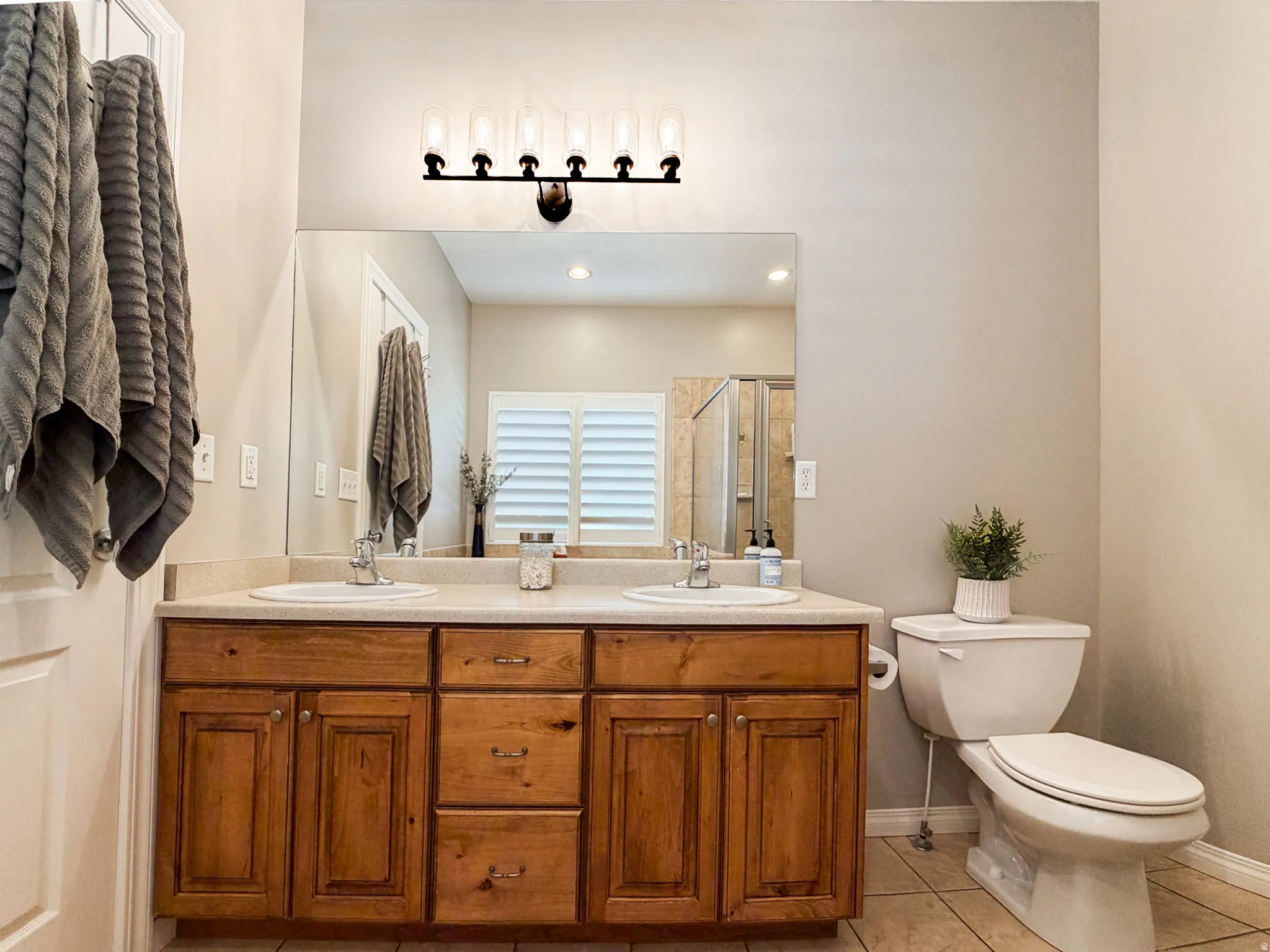 Dual vanity with wood-finish cabinetry, integrated sinks, and a single-piece mirror
