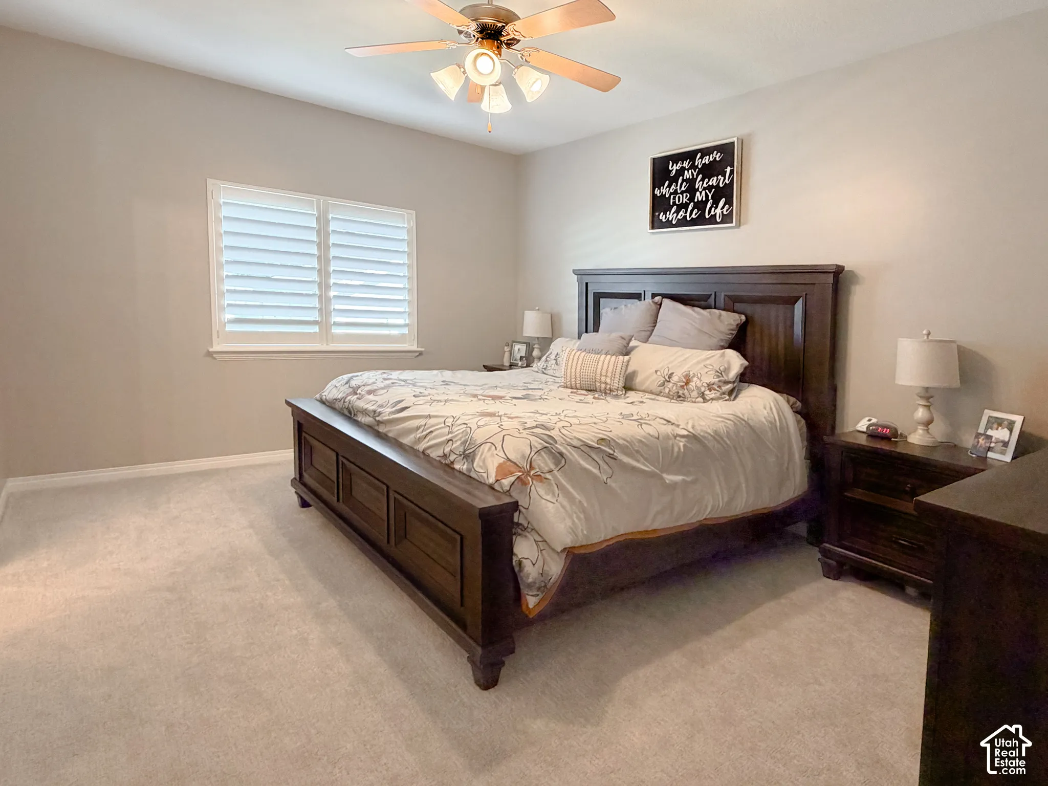Carpeted flooring, window with plantation shutters, ceiling fan with light fixture, and neutral wall tones