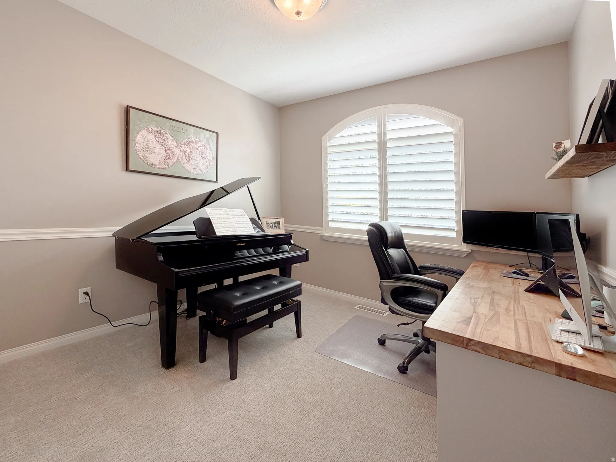 Arch-top window with white plantation shutters, light gray wall color, crown molding, white baseboards, and built-in wood-finish shelving