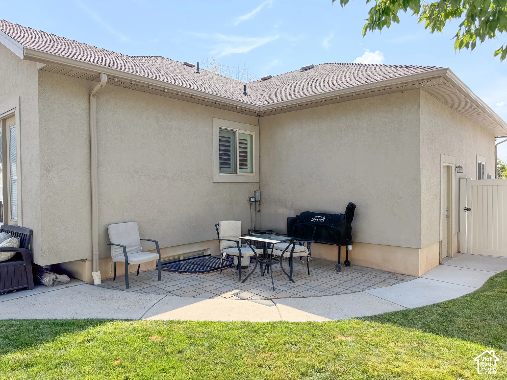 Stucco exterior with a pitched roof, featuring a paver and concrete patio area