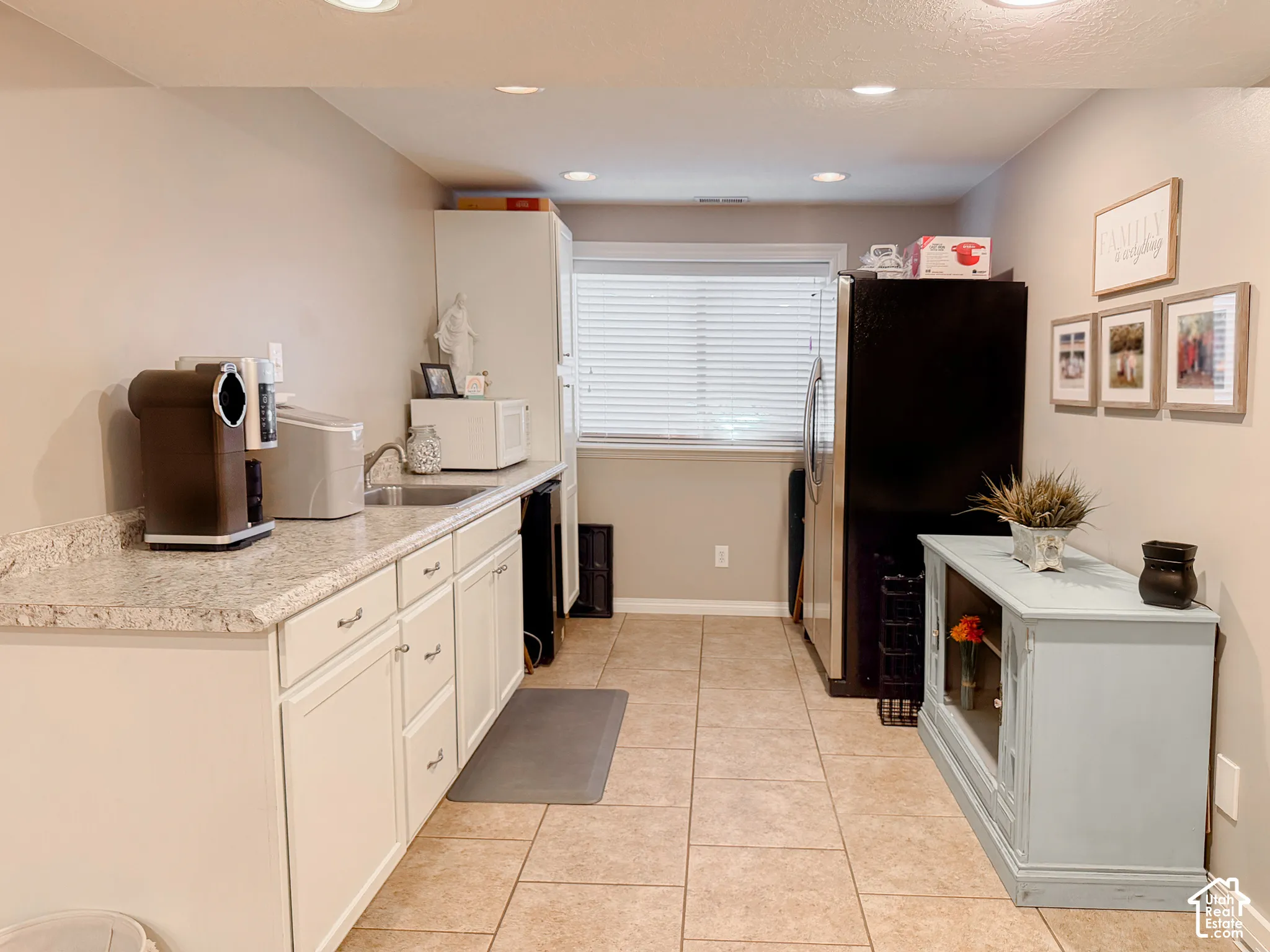Kitchenette featuring granite-finish countertops, white cabinetry, integrated sink, tile flooring, and recessed lighting