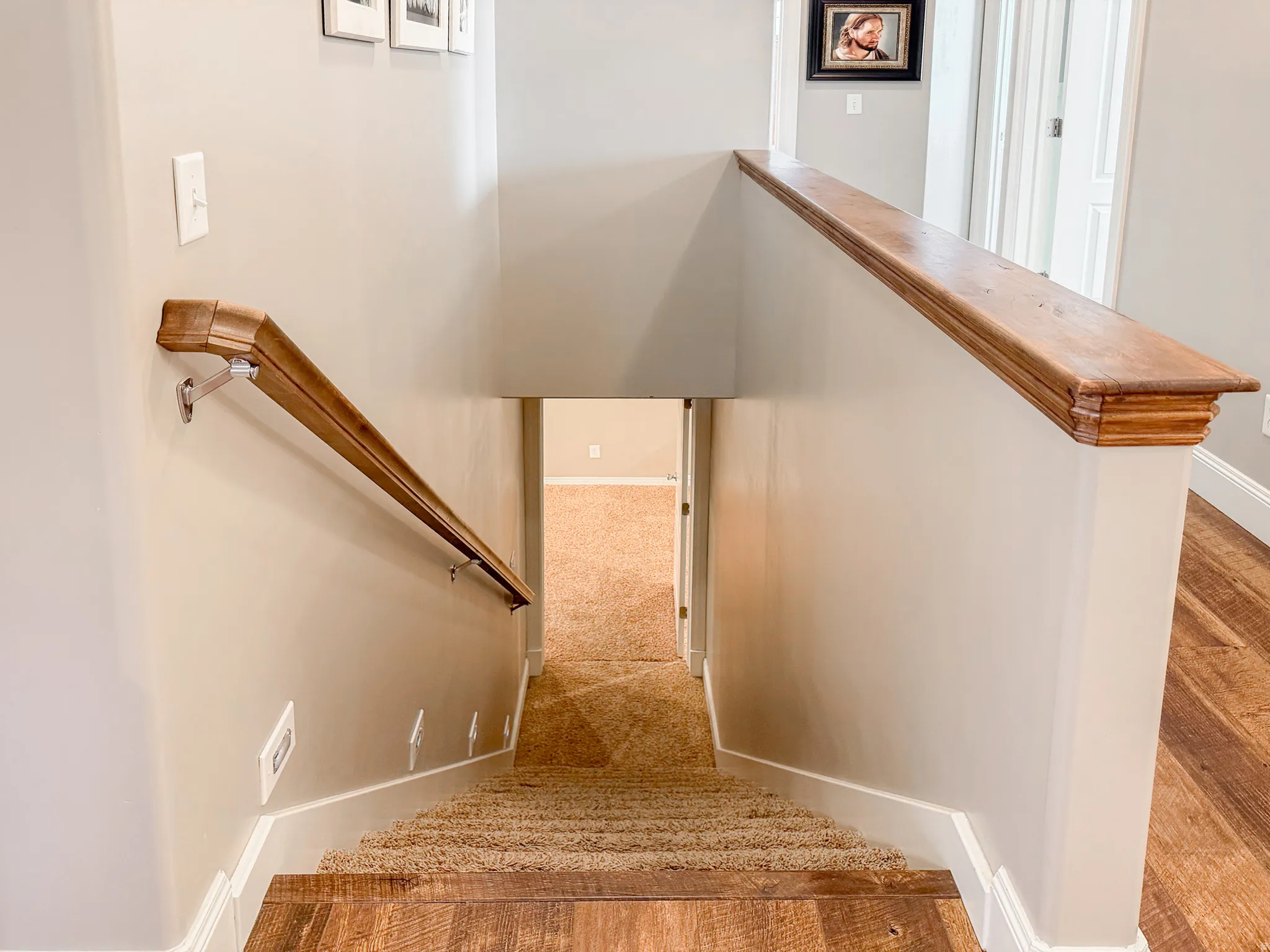 Carpeted staircase with wood-finish treads and risers, complemented by a wood handrail
