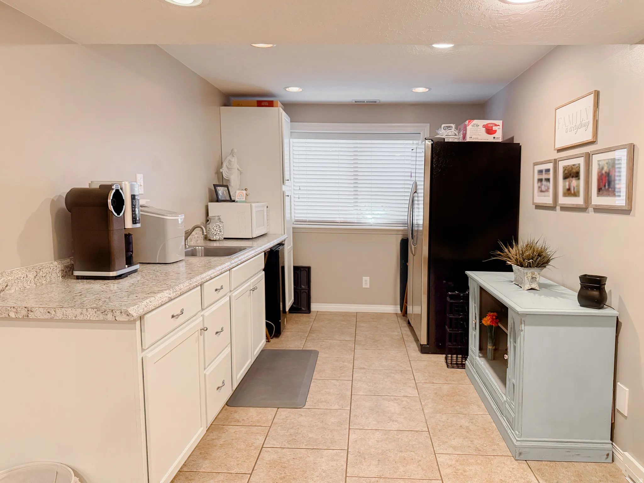 Kitchenette featuring granite-finish countertops, white cabinetry, integrated sink, tile flooring, and recessed lighting