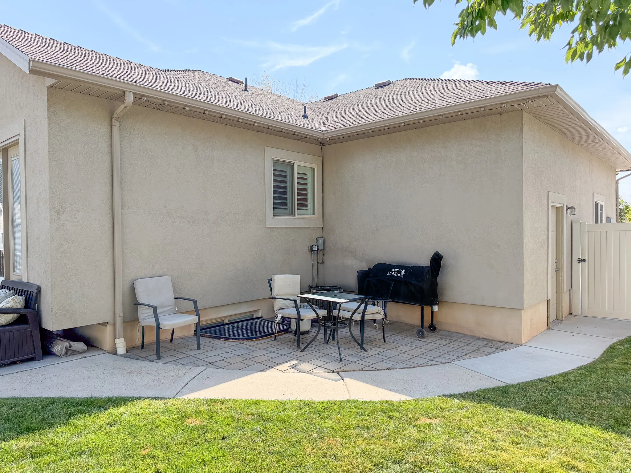 Stucco exterior with a pitched roof, featuring a paver and concrete patio area