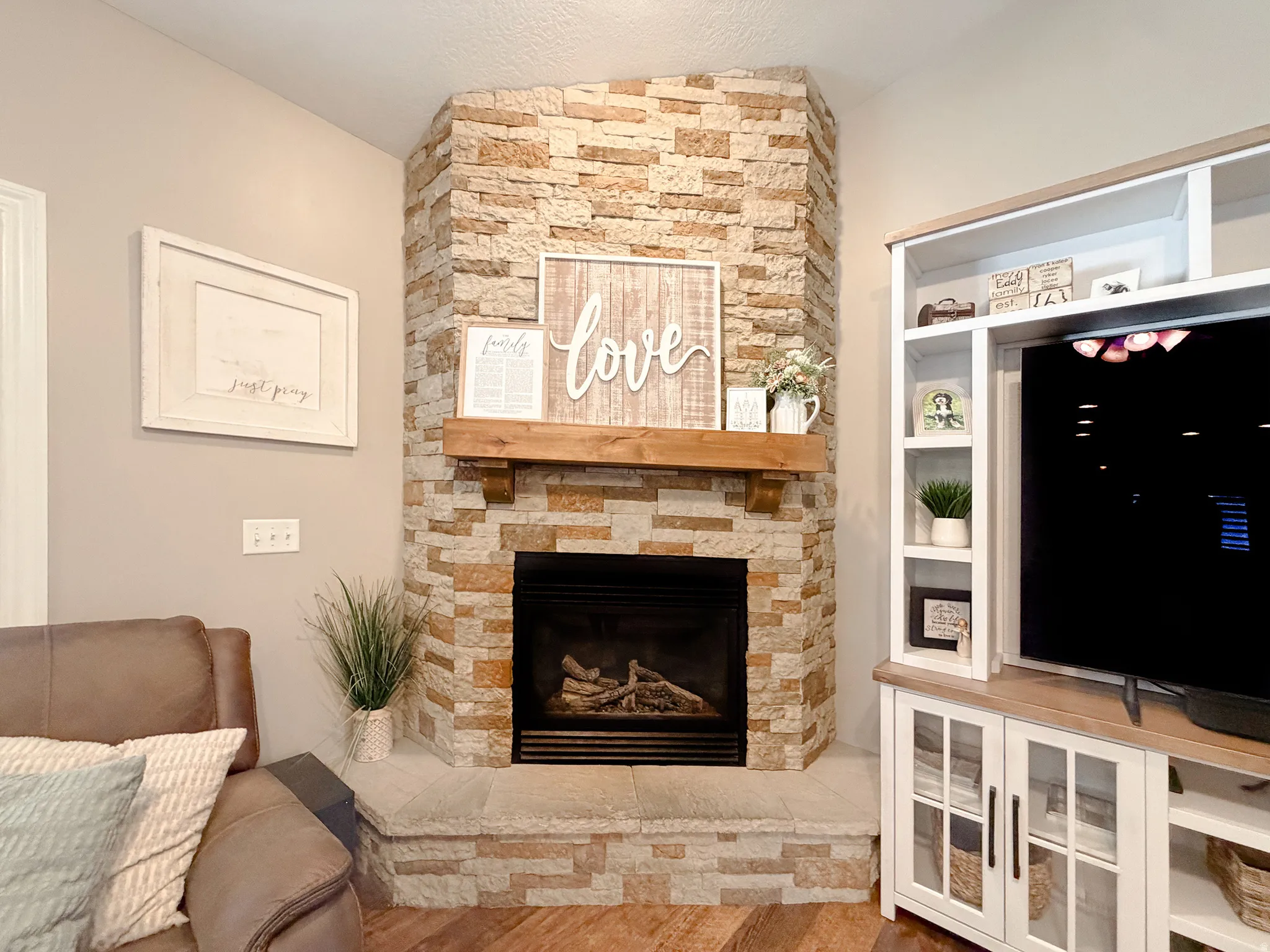 Corner fireplace featuring stacked stone surround, a wood mantel, and a stone hearth