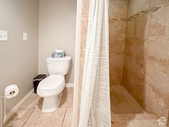 Walk-in shower with tiled walls and decorative accent band, tiled flooring, and a standard toilet