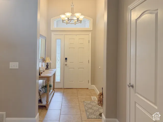 Entryway featuring a decorative chandelier, arched transom window, a tiled floor, and a paneled entry door with sidelight