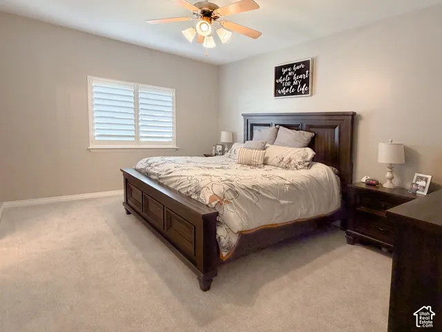 Carpeted flooring, window with plantation shutters, ceiling fan with light fixture, and neutral wall tones
