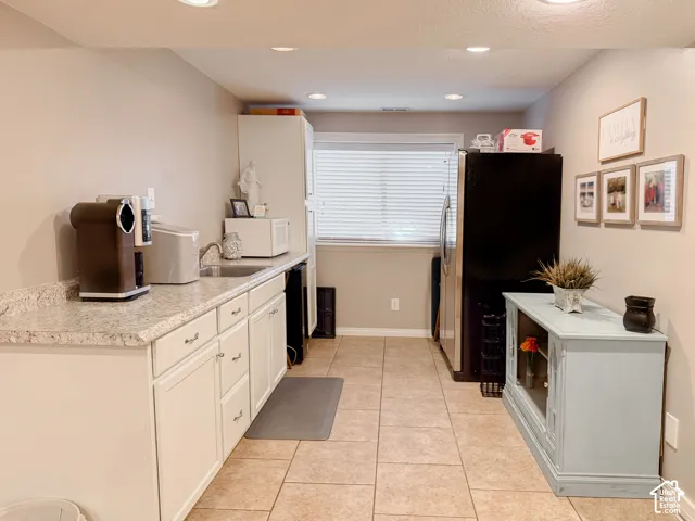 Kitchenette featuring granite-finish countertops, white cabinetry, integrated sink, tile flooring, and recessed lighting