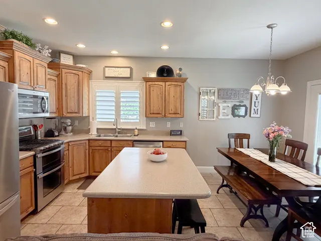 Kitchen with wood cabinetry, stainless steel appliances, recessed lighting, and a center island