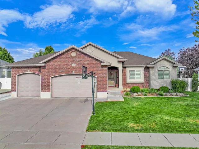 Brick and stucco exterior with a two-car garage, manicured lawn, and established landscaping
