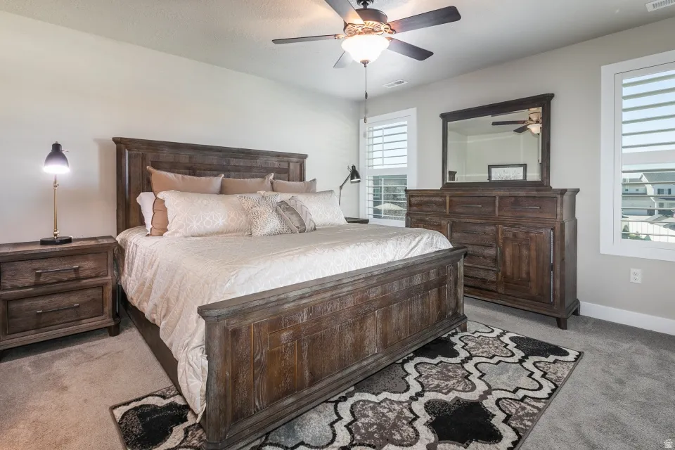 Recessed lighting, ceiling fan with integrated light fixture, two windows with white plantation shutters, and light gray wall paint