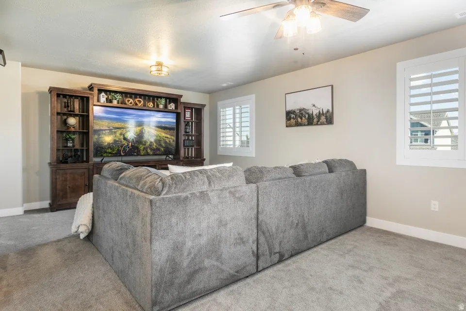 Built-in entertainment center, recessed lighting, ceiling fan, and window shutters