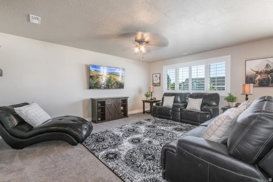 Recessed lighting, ceiling fan with light fixture, window with white plantation shutters, built-in entertainment console, and wall-mounted television