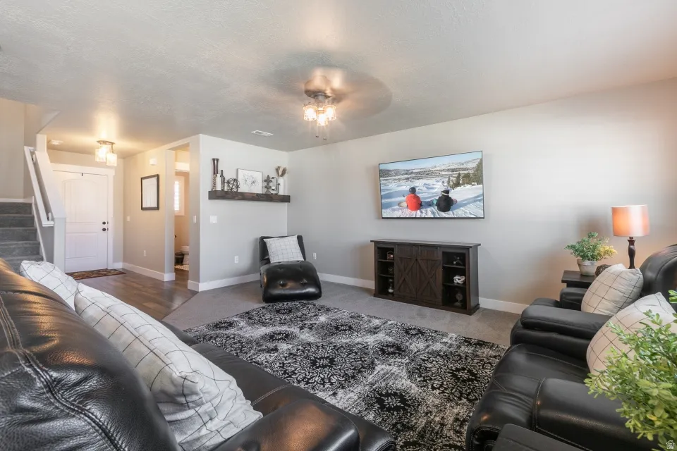 Spacious living area featuring neutral wall tones, carpet flooring, a built-in media console, and a contemporary ceiling fan