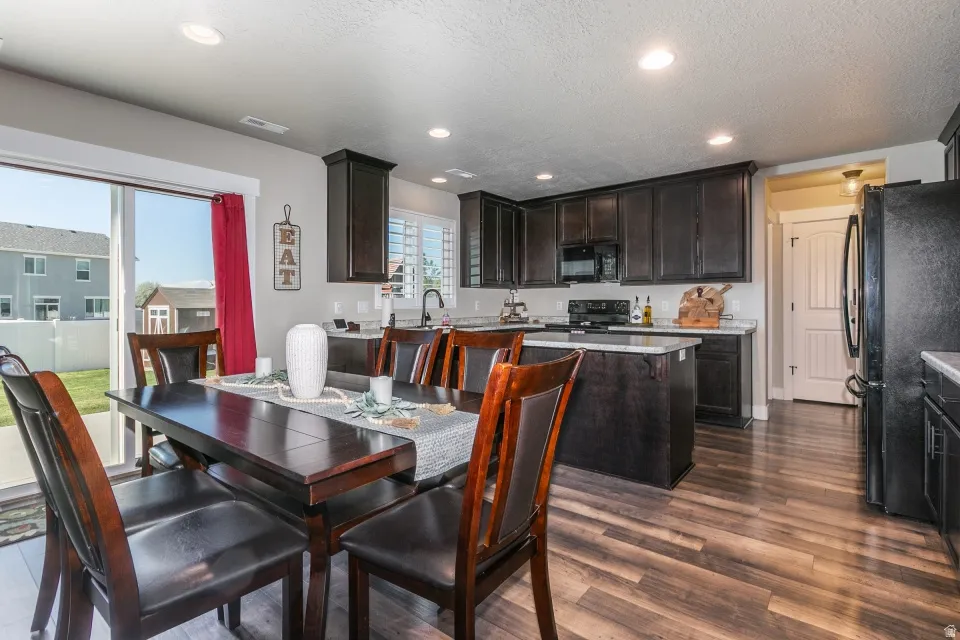 Open-concept kitchen and dining area featuring dark wood-finish cabinetry, light countertops, and wood-finish flooring