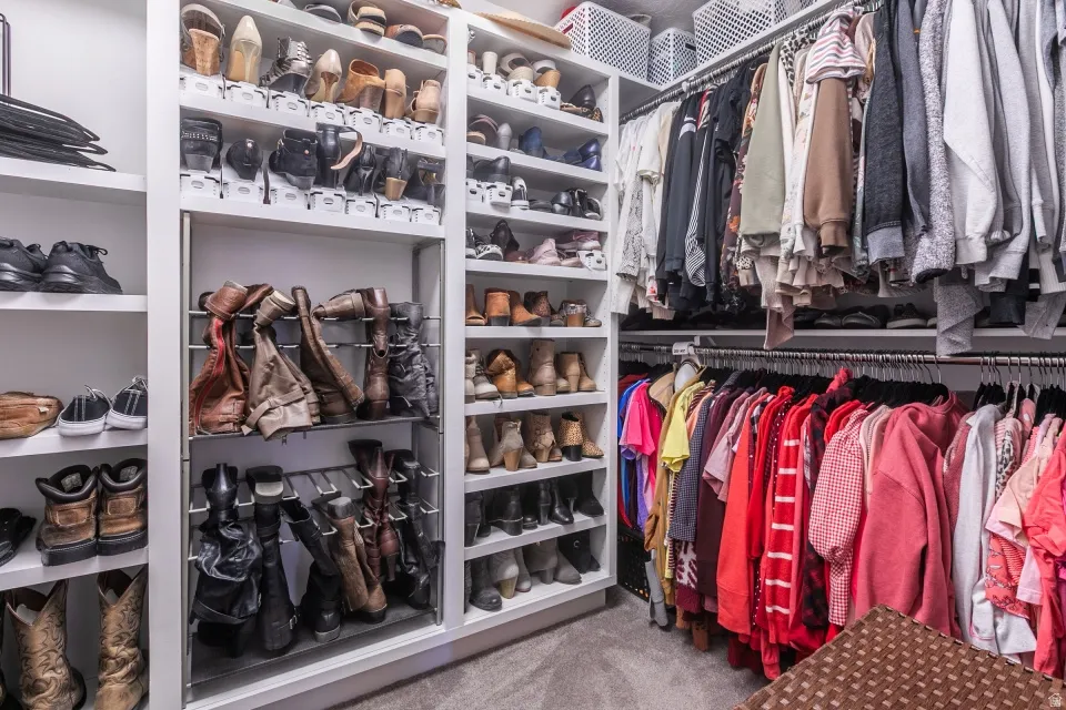 Expansive custom closet featuring built-in shelving, multiple hanging rods, and specialized shoe storage with pull-out racks