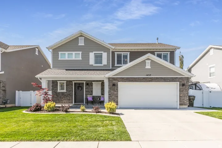 Two-story residence featuring a stone and siding facade, covered front porch, and an attached two-car garage