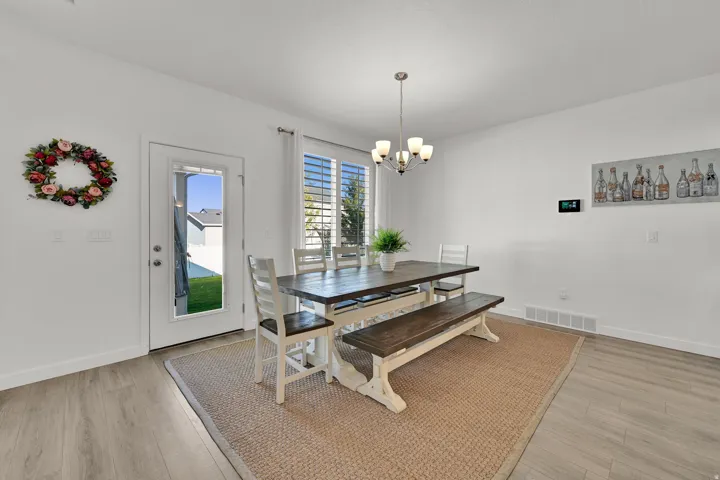 Dining space featuring wood-finish flooring, a contemporary chandelier, and a glass-paned door to the exterior