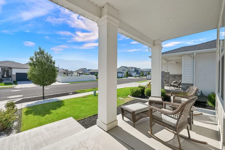 Spacious covered porch with robust white columns, concrete flooring, and recessed lighting
