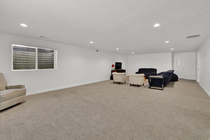 Spacious interior with neutral carpeting, recessed ceiling lighting, and crisp white walls