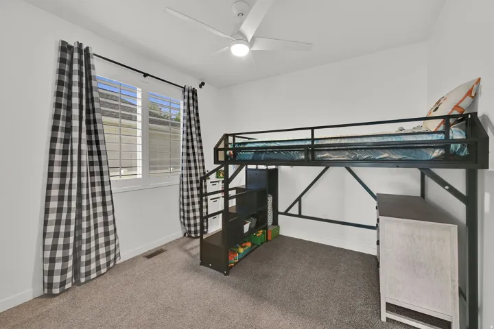 White walls, light gray carpet, and a ceiling fan with light fixture