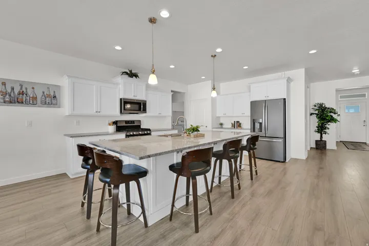 Contemporary kitchen featuring white cabinetry, a large center island with a light-colored countertop, stainless steel appliances, and recessed lighting