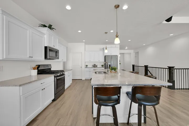 Kitchen featuring white shaker cabinetry, stainless steel appliances, granite countertops, and wood-finish flooring