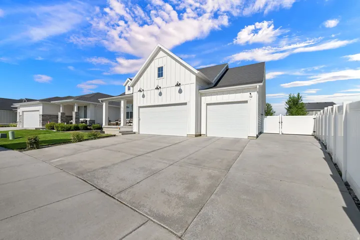 Modern farmhouse exterior with white board and batten siding, dark shingle roof, two garage doors, and a concrete driveway