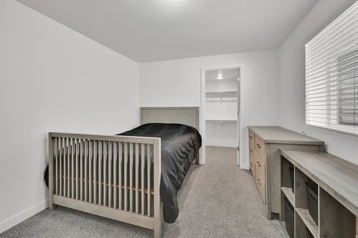 Neutral wall colors, carpet flooring, window with blinds, recessed lighting, and a walk-in closet with built-in shelving