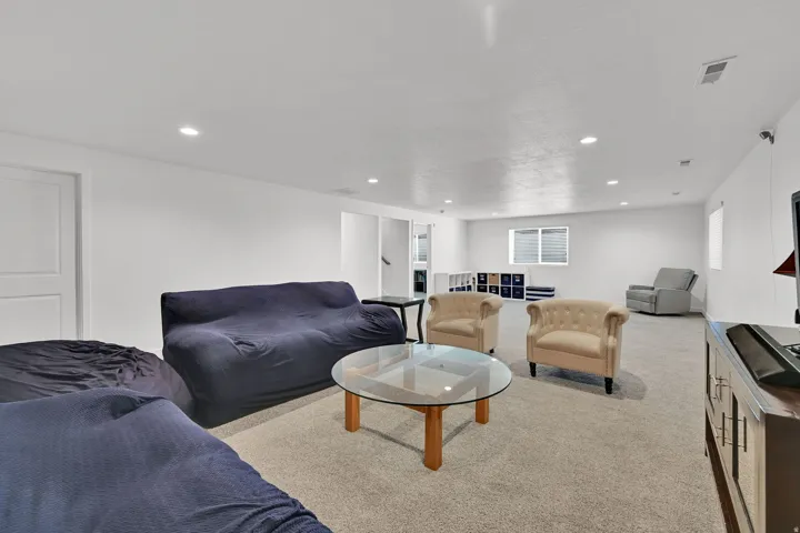 Recessed lighting, light-toned carpeting, ample wall space, and a window for natural light