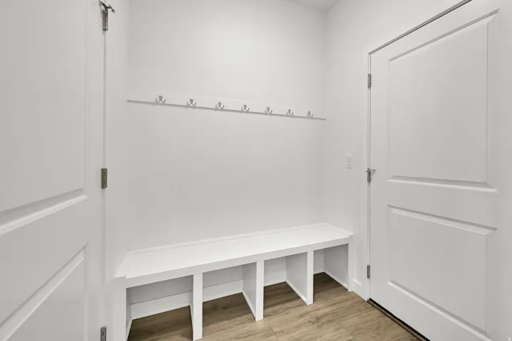 Built-in hall tree with storage bench, wall-mounted coat rack, and wood-finish flooring