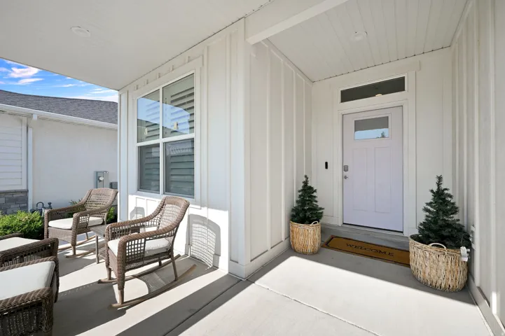 Covered front porch with concrete flooring, vertical board and batten siding, and recessed lighting