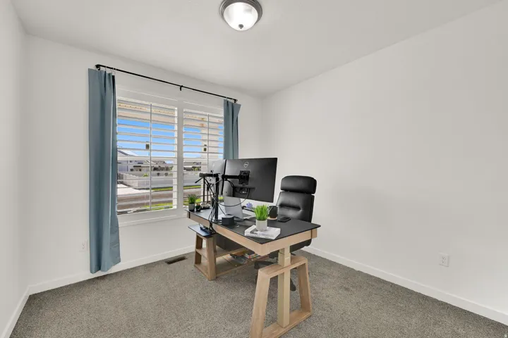 Carpeted room featuring a window with integrated shutters, white walls, and a flush mount ceiling light