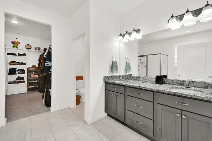 Dual vanity with granite-style countertops, gray shaker-style cabinetry, and brushed nickel hardware